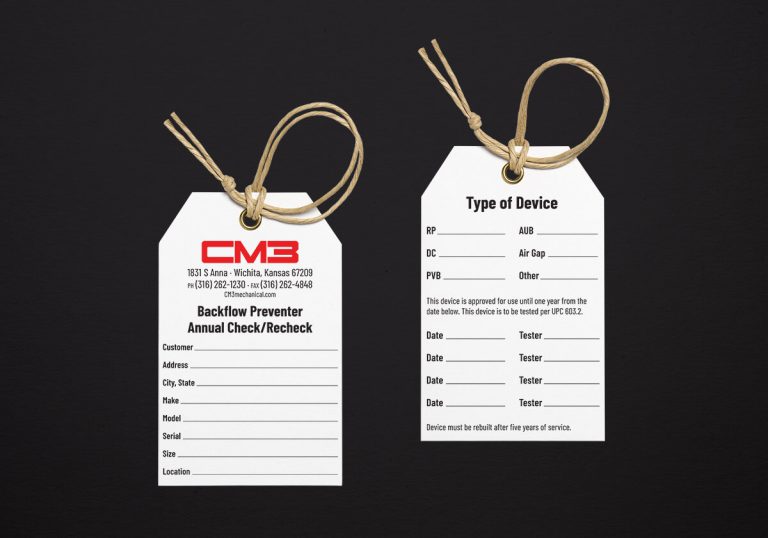 The front and back of the CM3 backflow tag displayed side by side on a dark background. The tag is white with black and red details.