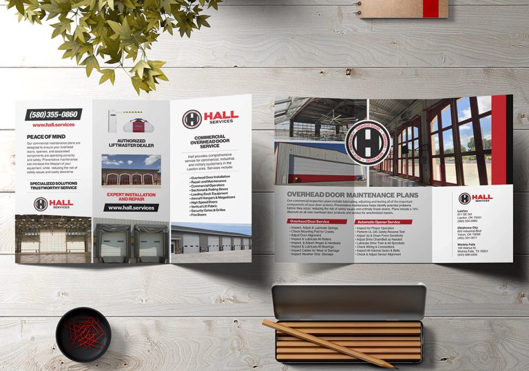 Hall Services trifold brochure open on wooden table with plant and pencil case.