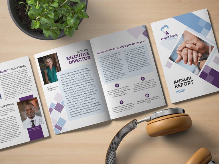 The Project Access 2022 Annual Report lays open on a wooden table. There is also a plant and a set of headphones.